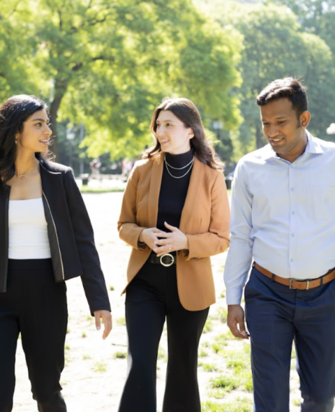 Three students walking and smiling at each other