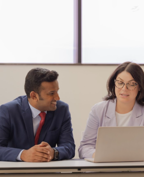 Two students sitting looking at a laptop
