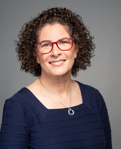 Laura Towey is a white women with short surly brown hair on a grey background.