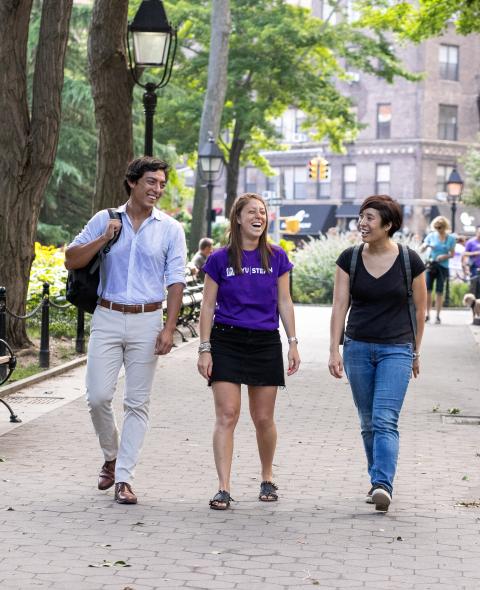 A group of three Stern students walks in Washington Square Park A group of three Stern students walks in Washington Square Park