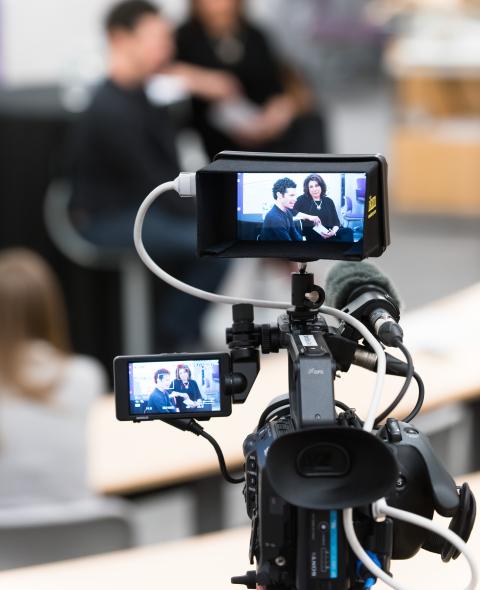 Close up of a camera filming two people in an interview