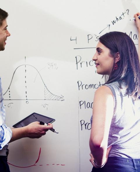 Two students writing on a whiteboard