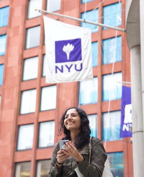Student on phone stands in front of Stern