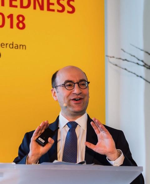 Steven Altman speaks at a podium in front of a yellow banner