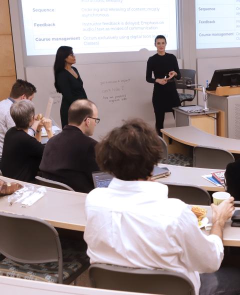 Two presenters stand in a classroom giving a workshop to faculty