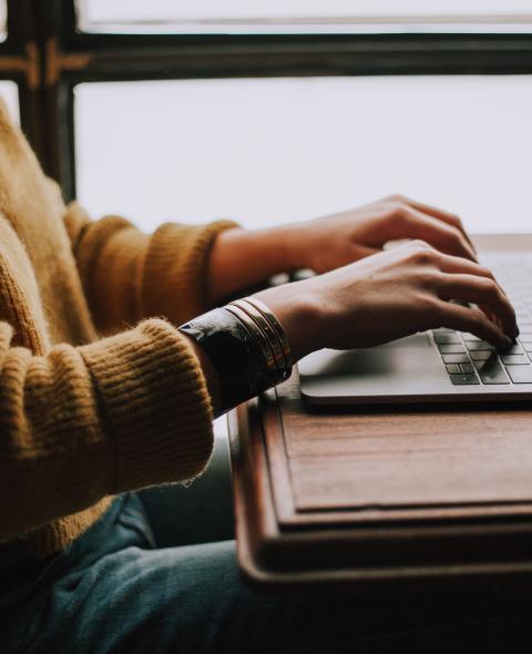 Student typing Student typing in yellow sweater
