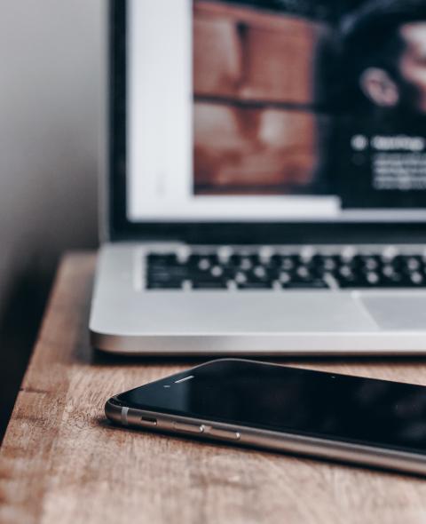 Open laptop and iphone on wooden table