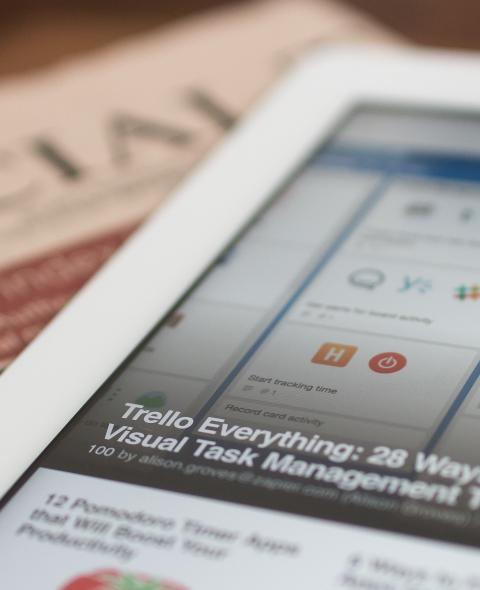 A newspaper and computer tablet laying on a table