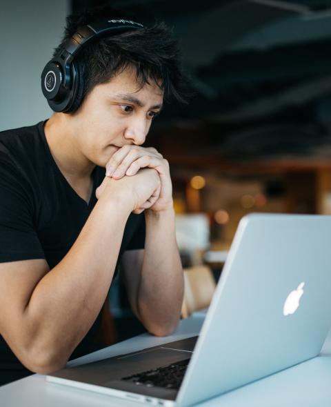 Student wearing headphones looks at a laptop