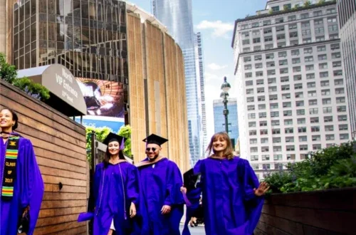 Four students in caps and gowns walking outside