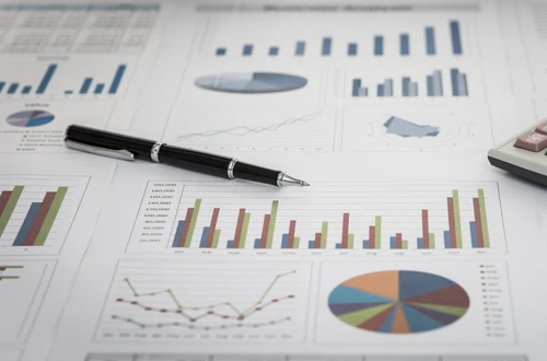 A pen and calculator on top of paper with charts