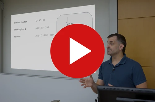 An instructor at a lectern, presenting a worked example