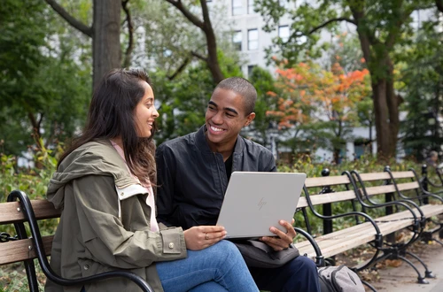 Stern students sit on a bench with a laptop
