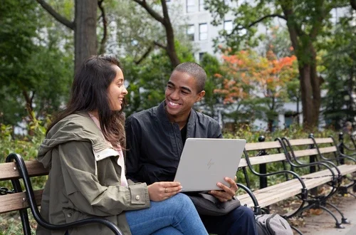Stern students sit on a bench with a laptop