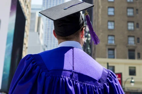 Graduate in cap and gown looking at Empire State Building