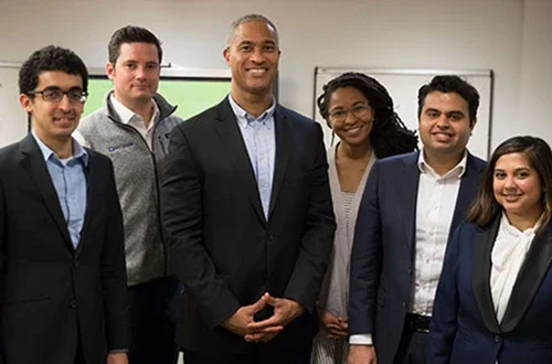 Five students and professor standing in conference room