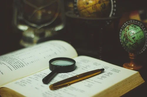 Book with magnifying glass and pen