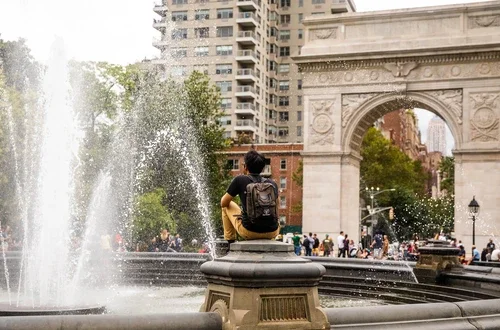 Student sitting near fountain in front of Washington Square Arch
