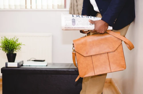 Person holding briefcase and newspaper