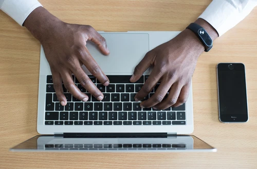 Hands type on a laptop keyboard