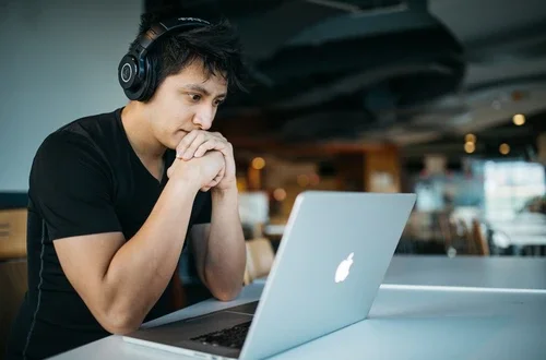 Student wearing headphones looks at a laptop