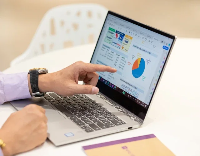 man pointing to laptop screen which displays various colorful charts and graphs.