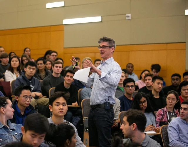 Professor speaking while standing in a crowd of seated students