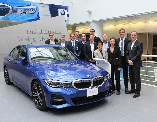 A smiling group of people standing beside a blue car