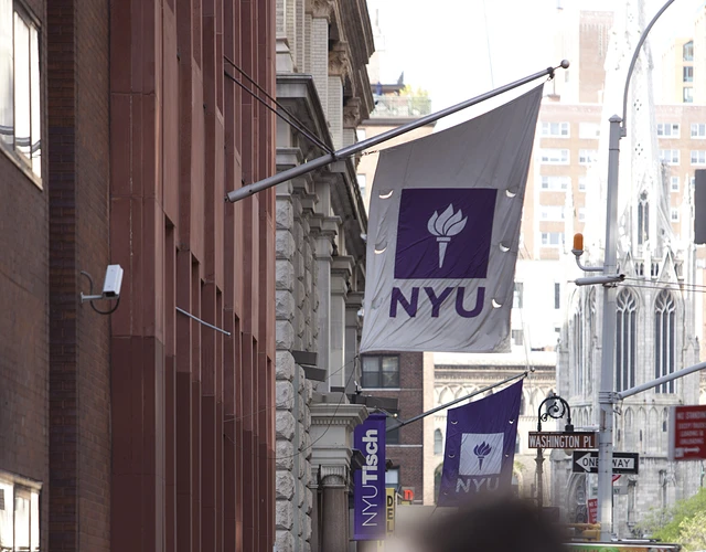 View of sidewalk with blurry crowds below an NYU Banner