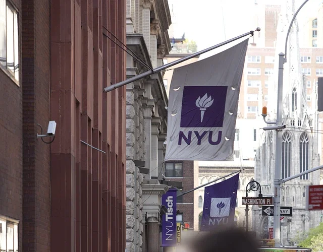 View of sidewalk with blurry crowds below an NYU Banner
