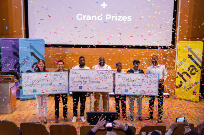 Six people holding oversized checks with confetti falling over them