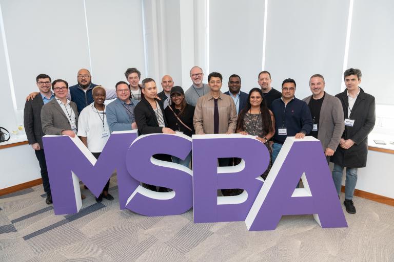 MSBA 10 year anniversary celebration. A group of MSBA Alumni stand behind large letter stands that spell MSBA. 