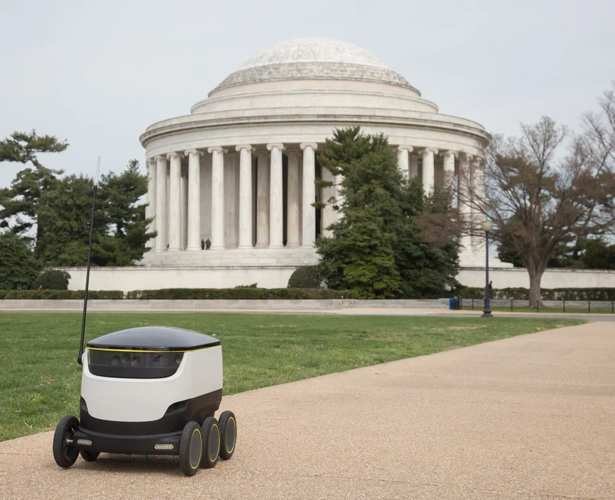 a small robot in front of a dc building beep boop