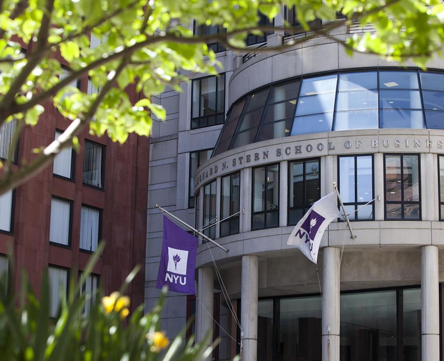This is an image of the entrance of NYU Stern, a gray building with flags.