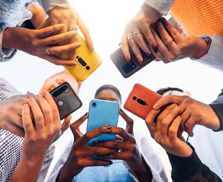 Five people standing in a circle looking at their phones