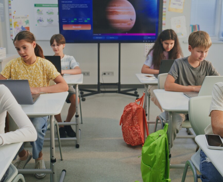 Six elementary school students at their own desks typing on a laptop computer