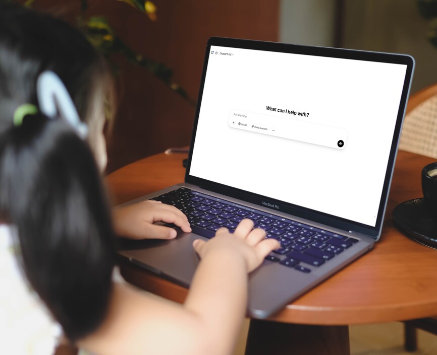 A young child at a laptop typing into ChatGPT