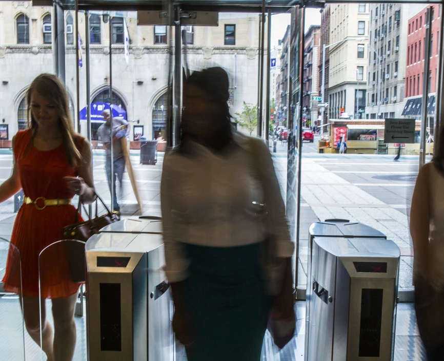 Students walking into a building through glass turnstiles