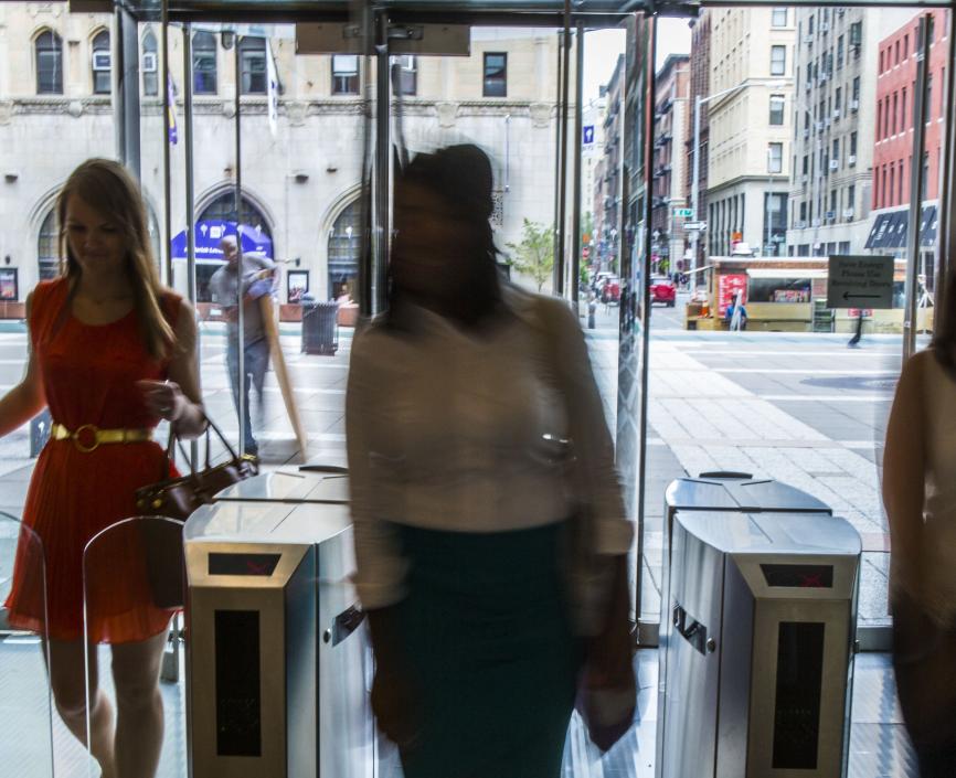 Students walking into a building through glass turnstiles