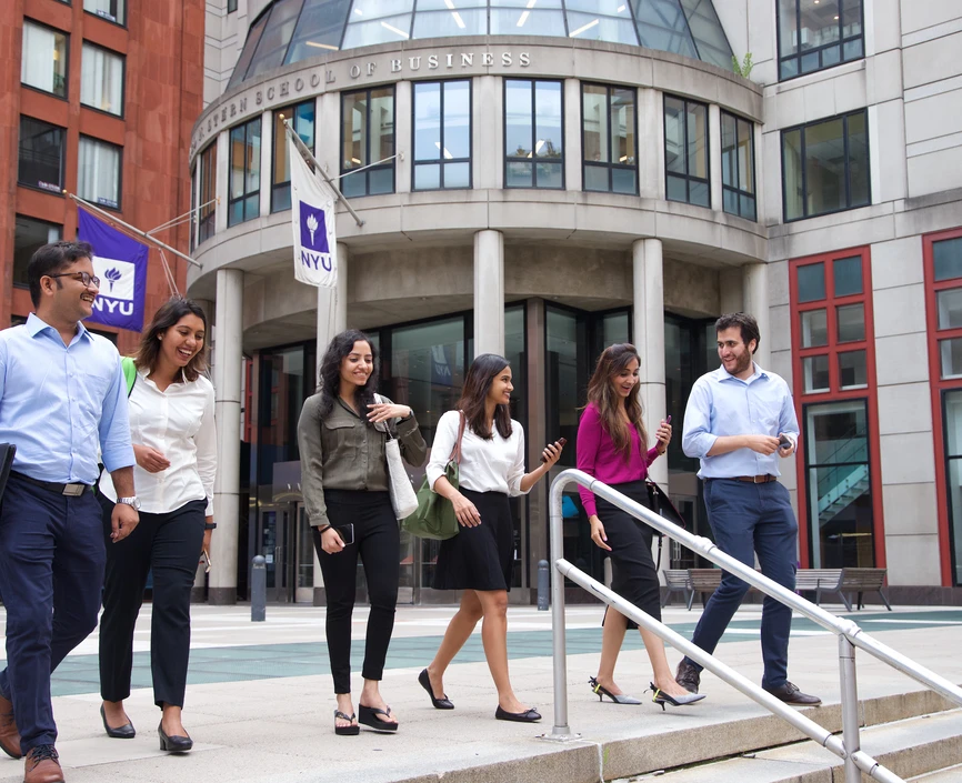A group of people walking down the steps in front of an NYU building