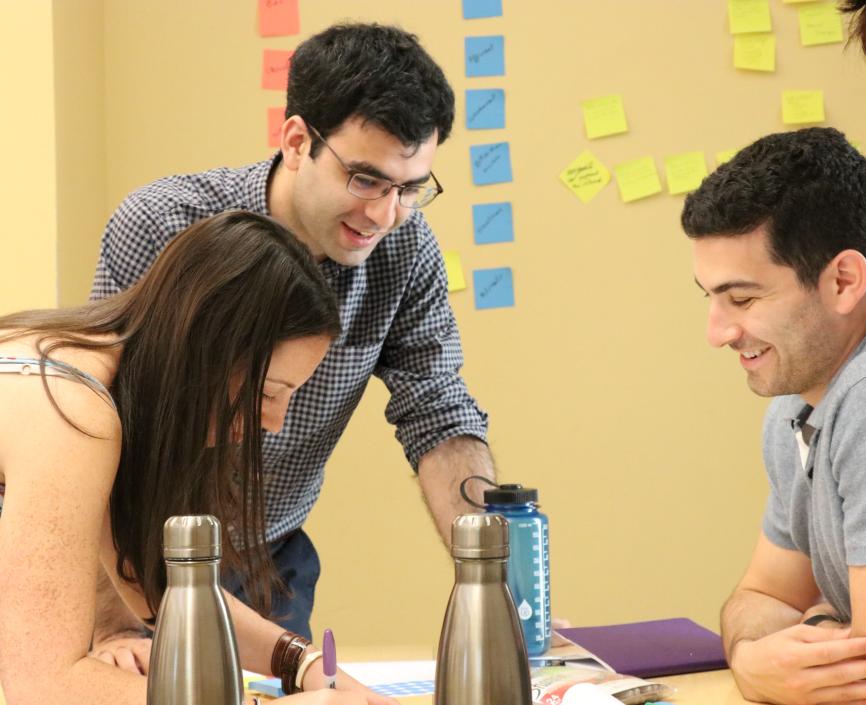 Tech MBA students writing and smiling while solving a problem