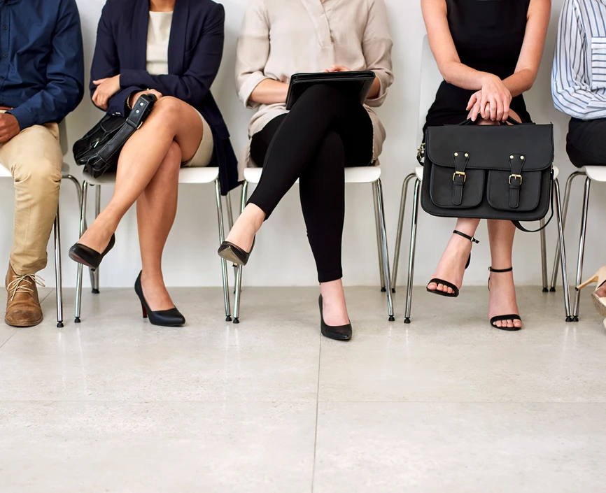 five people in business wear sitting on chairs, viewable only from the shoulders down