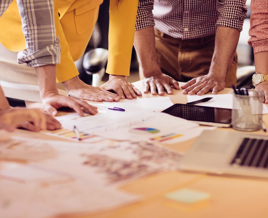 A group of people standing around a table working 