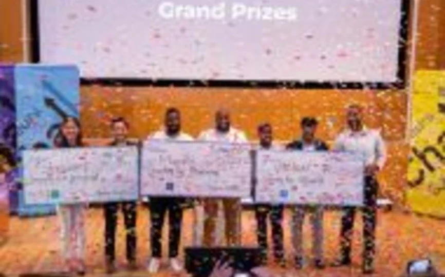 Winning teams stand on stage with prize checks as confetti falls