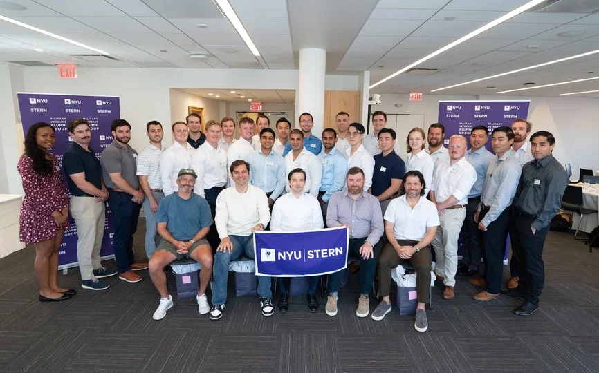 Military Veteran alumni hold an NYU Stern banner for a group photo