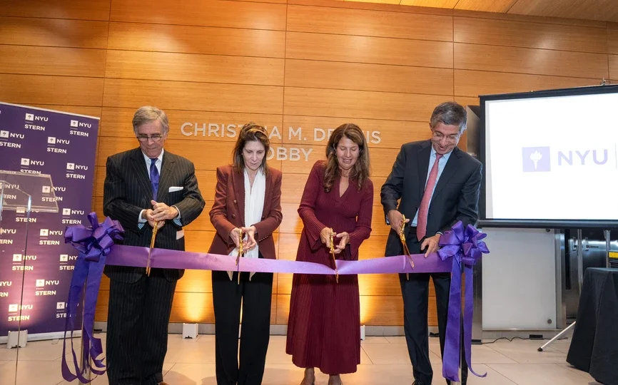 Four people use scissors to cut a large violet ribbon
