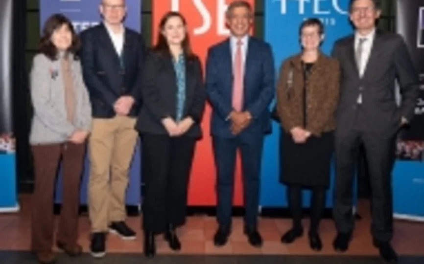 Six members of TRIUM leadership stand in front of banners with the TRIUM logo and logos from NYU Stern, LSE and HEC