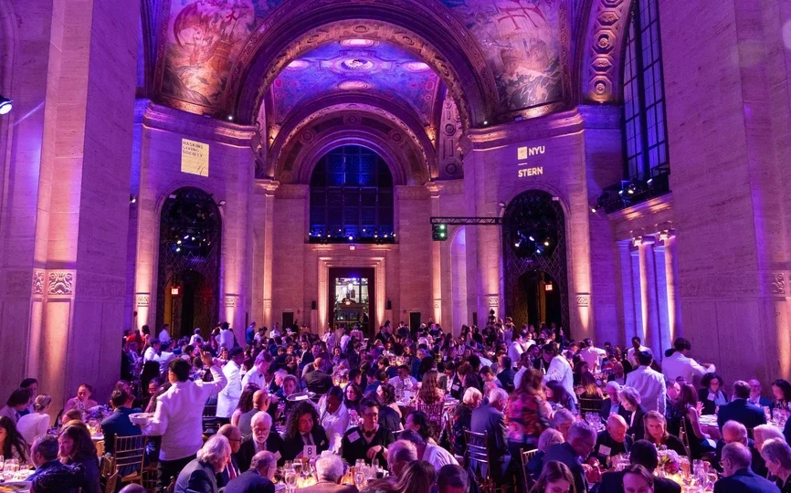 A room lit in violet with tables filled with people