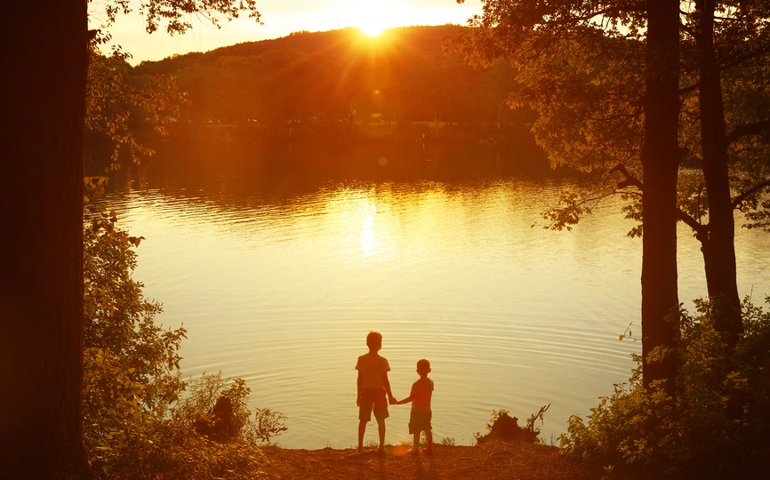 Two kids in front of a lake at sunset