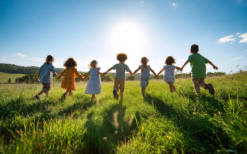 7 kids holding hands running in a field
